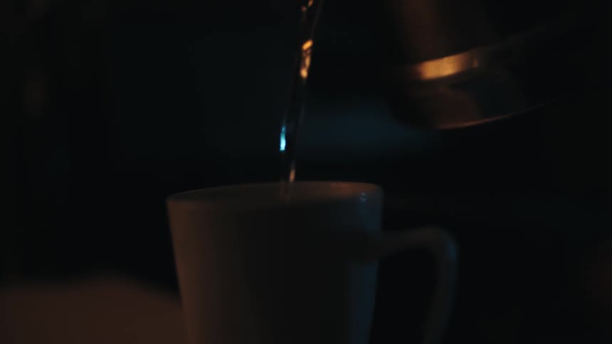 A beverage being poured in to a mug