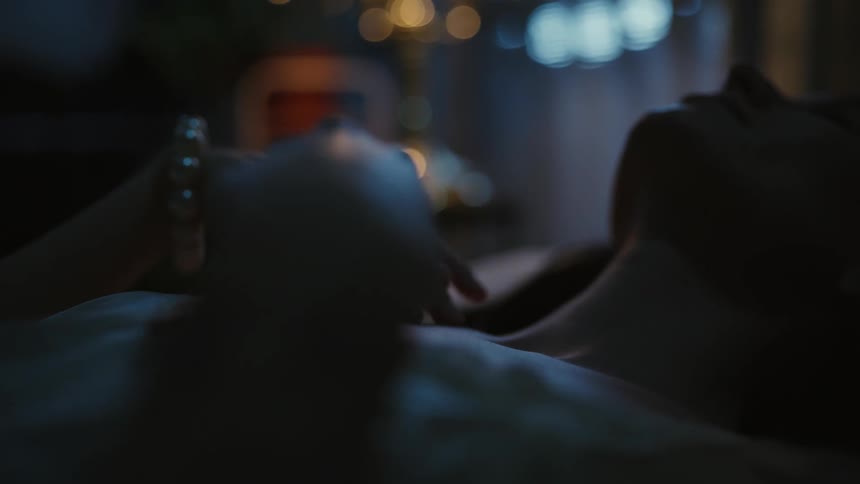 Woman strokes hand across another persons chest as they lie in bed