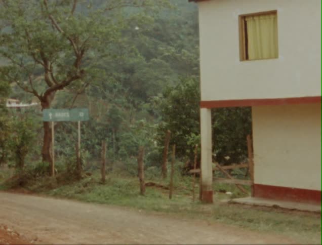 A dirt road near a home with tree covered land