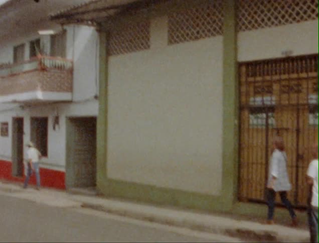 Pedestrians walking down the street of a small town caught on vintage film