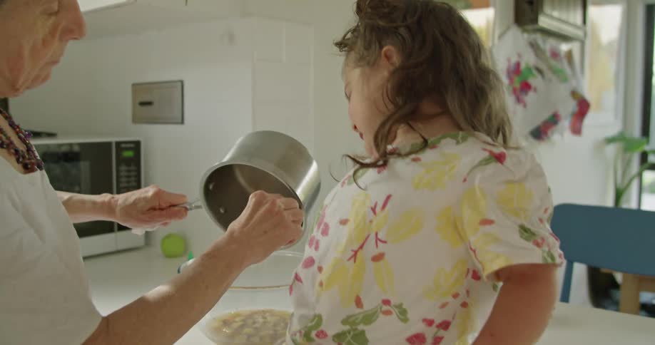 A child watches her grandmother cook in the kitchen