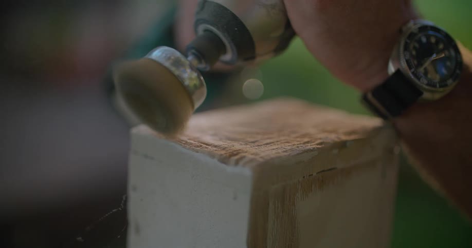 A person is shaving wood with a drill tool