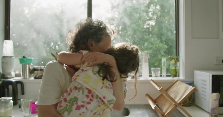 A grandmother dips her granddaughter in her arms