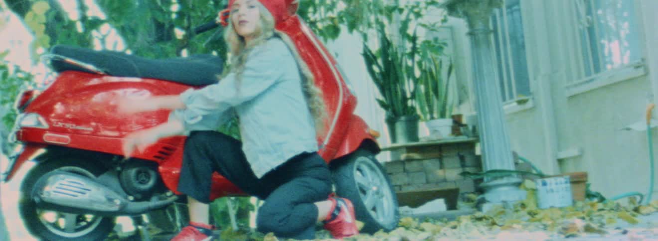 A woman posing next to her scooter outdoors