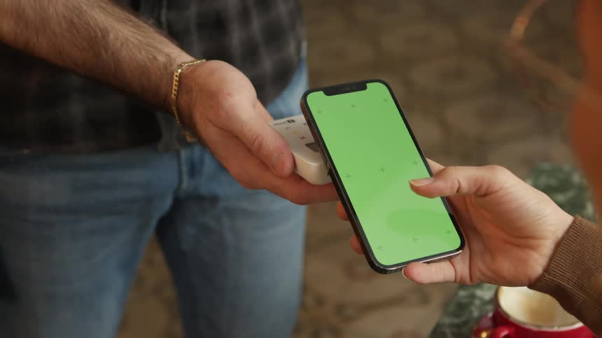 Customer pays bill with smartphone as merchant uses hand held point of sale device