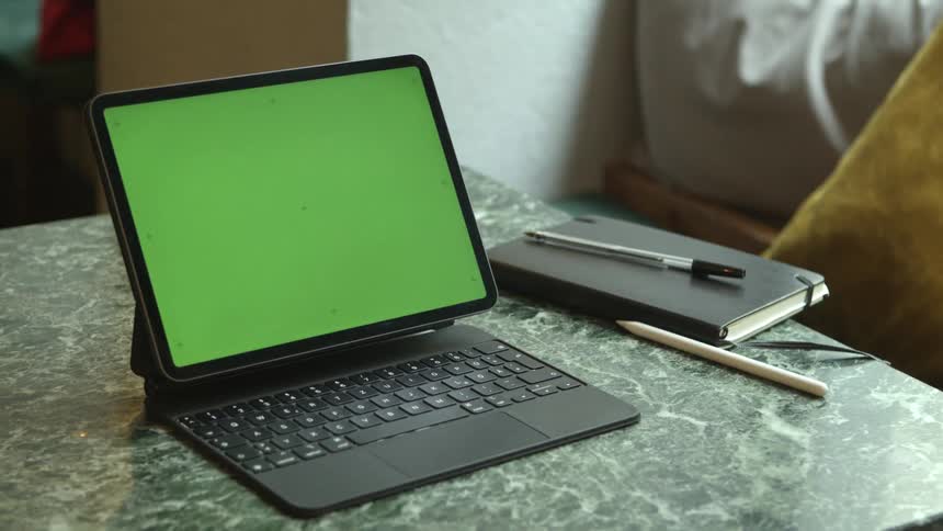A woman taps the screen of laptop while sitting at a table indoors during the day