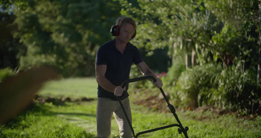 A man is mowing his lawn on a windy day