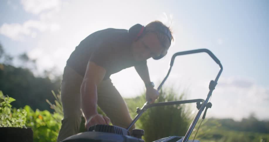 A man attempts several times to start a lawn mower