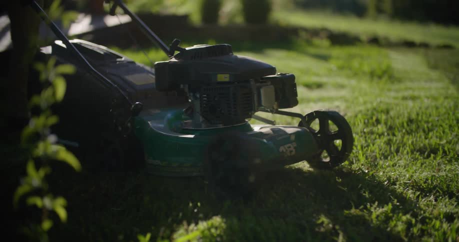 A man uses a push lawn mower on his lawn