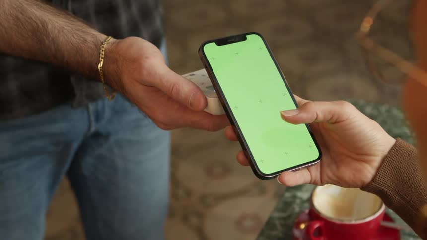 Woman uses her smartphone with a green replaceable screen to pay the bill