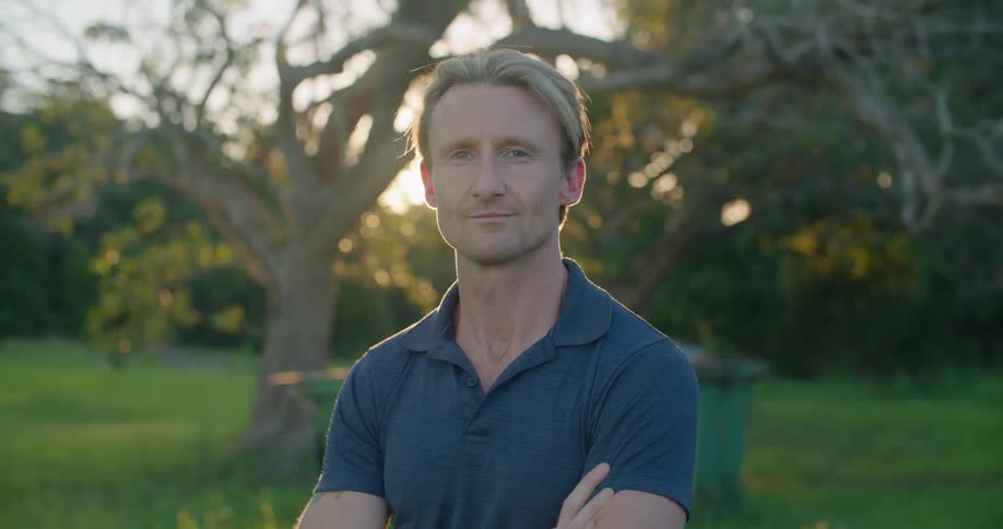 A man is standing in his yard on a sunny day