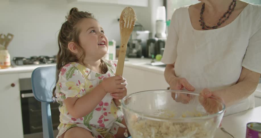Grandmother and granddaughter happily cooking in the kitchen at home