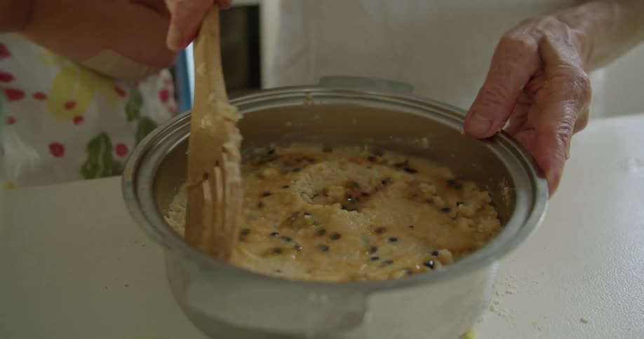 A man spins a pan around to smooth out the surface of a chocolate chip cake