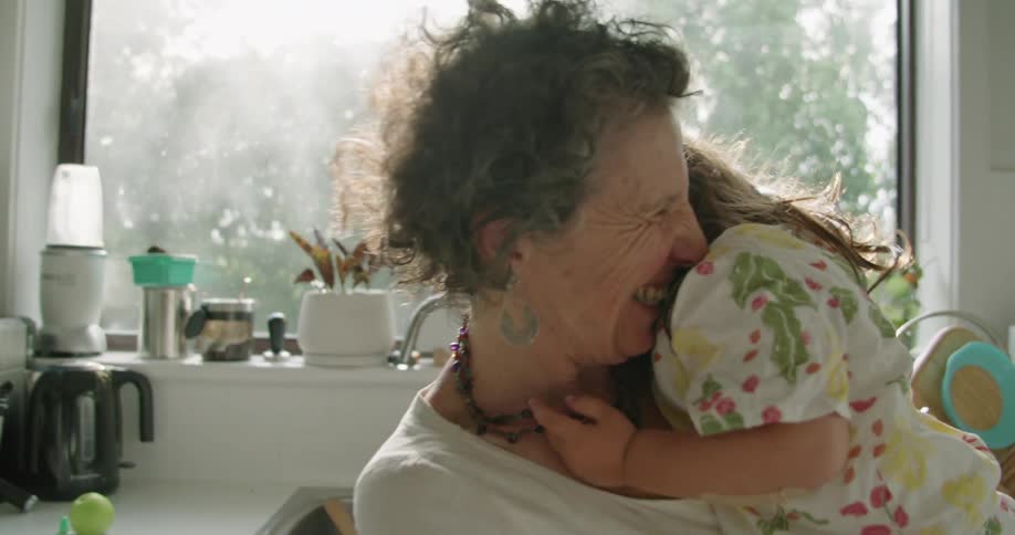 A grandmother is hugging her granddaughter and rocking her