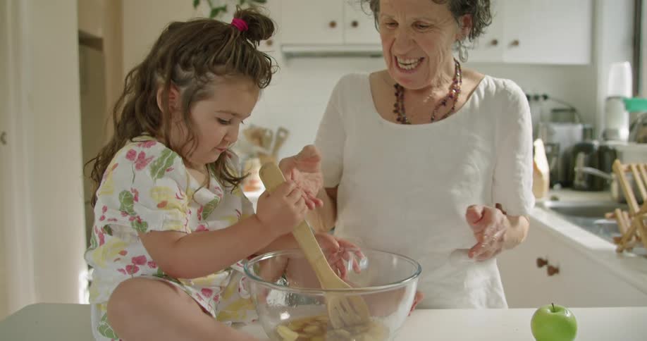 A grandmother and granddaughter cook in the kitchen