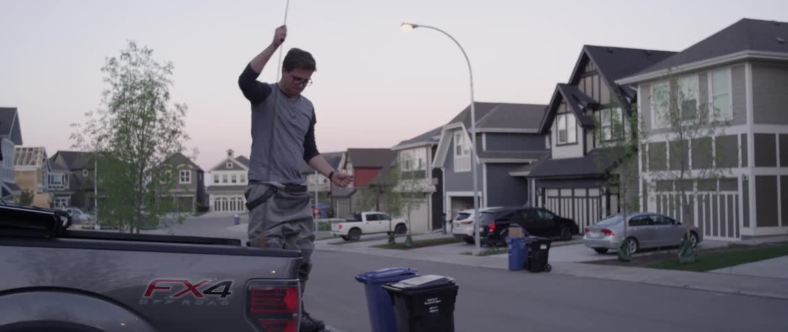 A man sets up his fishing pole standing on the end of his truck