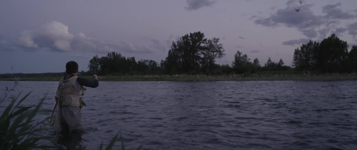 A man is fly fishing in the middle of a lake