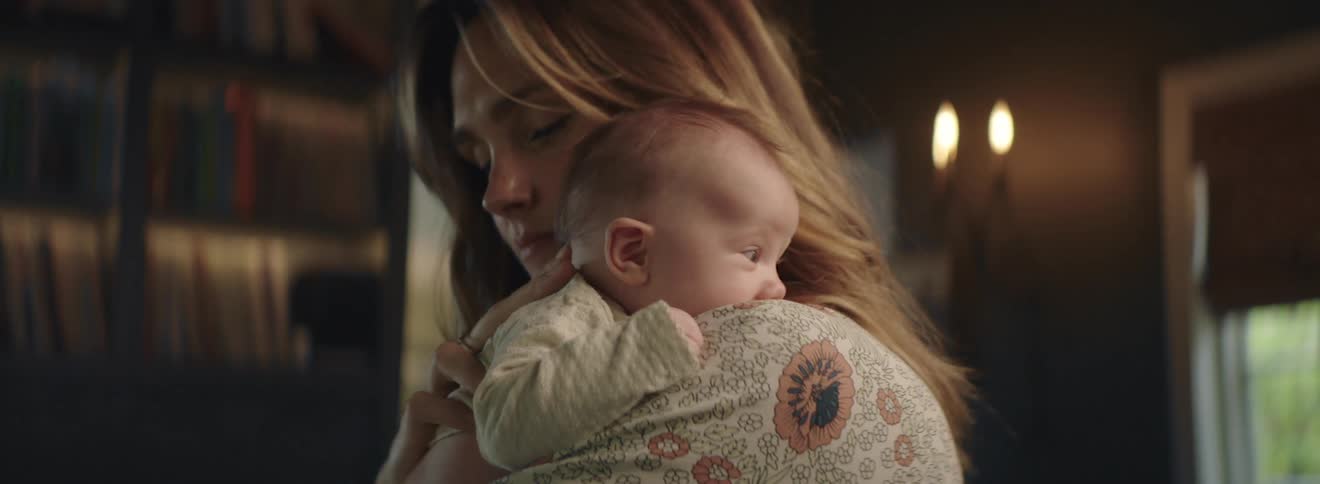 A woman is rocking her baby slightly as she holds them