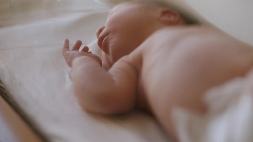 A newborn baby sleeps as they lay in bassinet