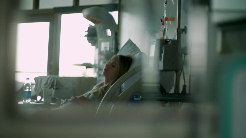 A pregnant woman lies in a hospital bed surrounded by medical equipment