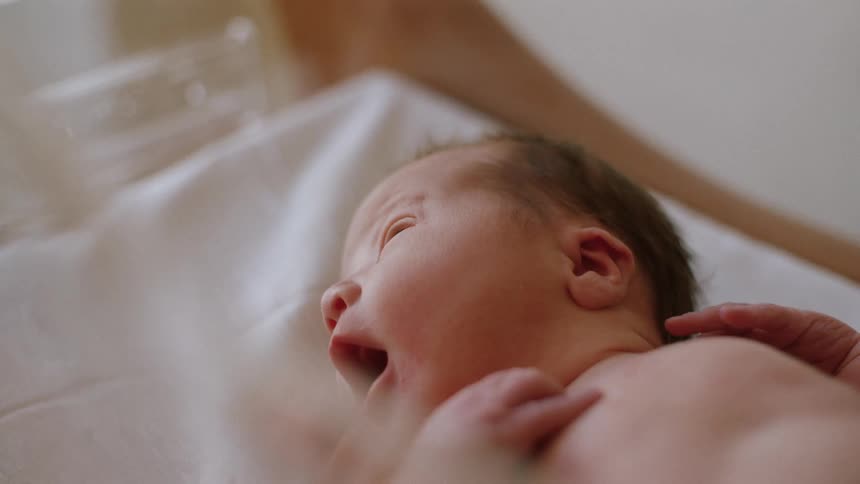 A newborn rests in the bed