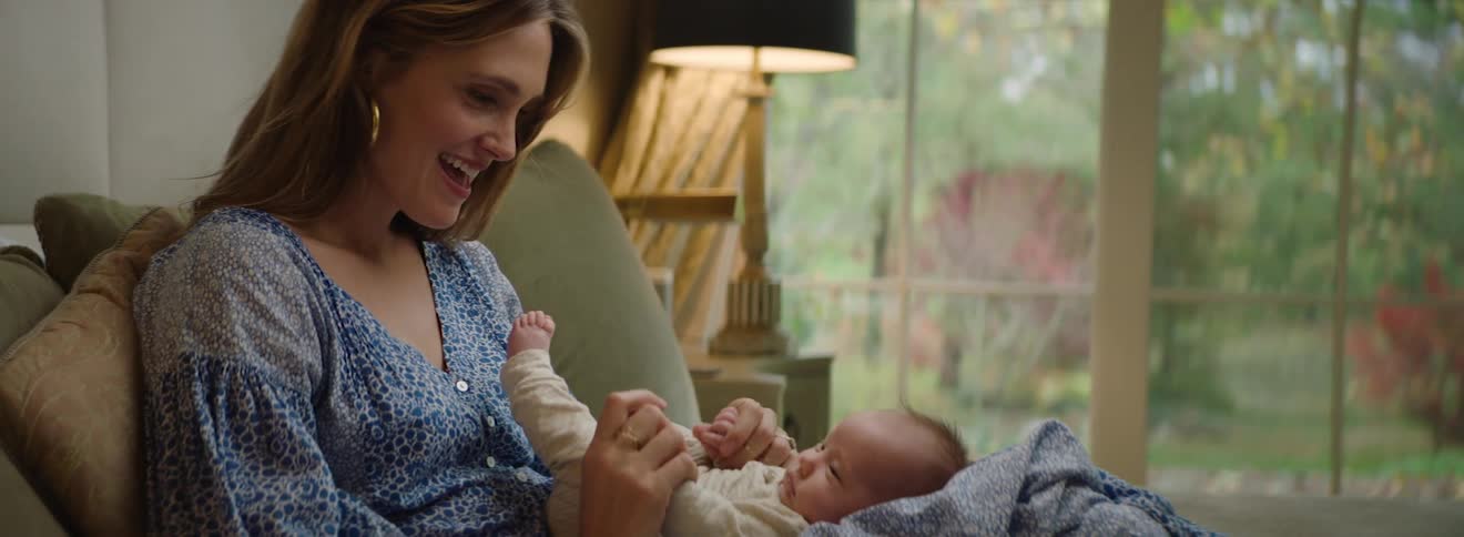 A woman smiles at her baby while playing with it in her lap