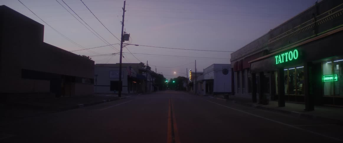 Neon lights in a store light up a very dark street in a small town