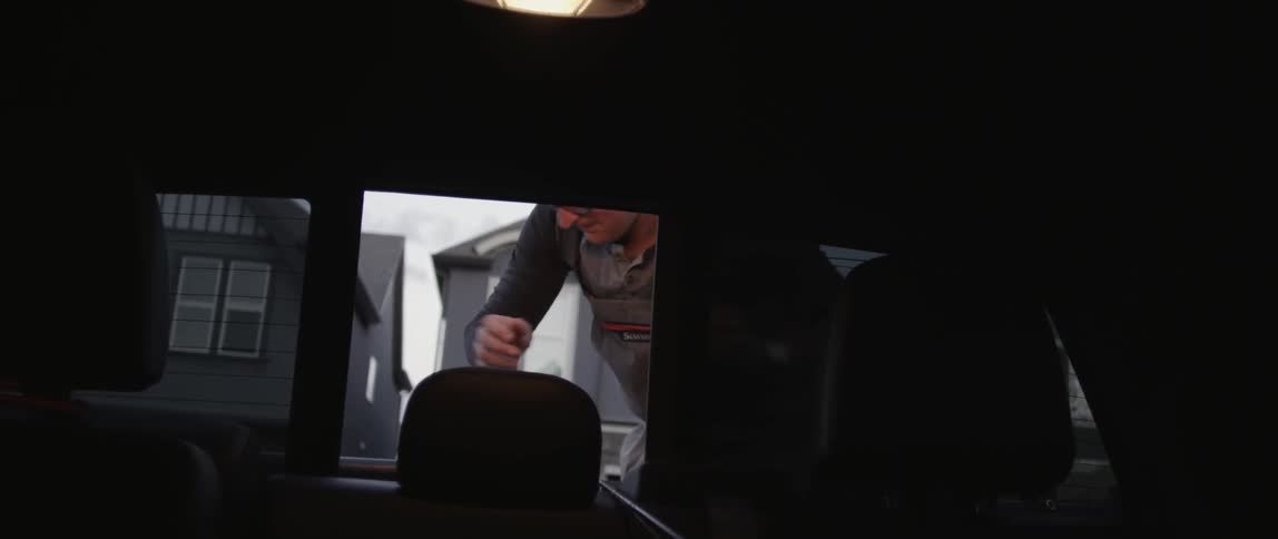 A person puts a fishing pole in a car