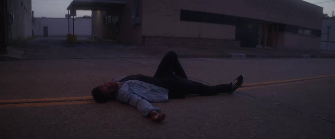 A woman lies in the middle of a city street