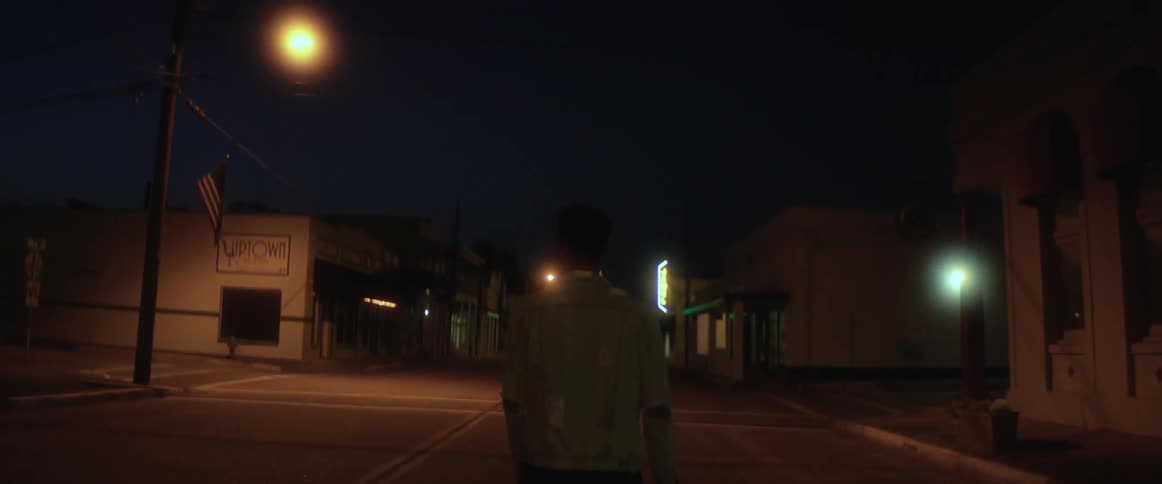 Young man walking down the dark street of a small town at nght