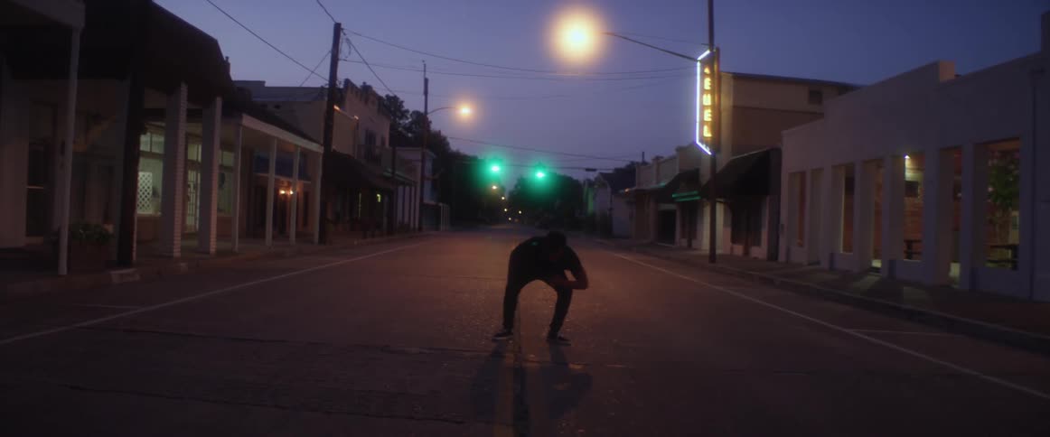 A man is stumbling around in the middle of a street in a small town