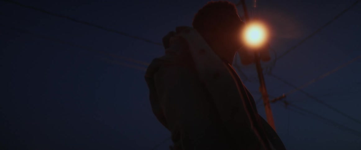 Silhouette of a young man standing under a streetlight at night