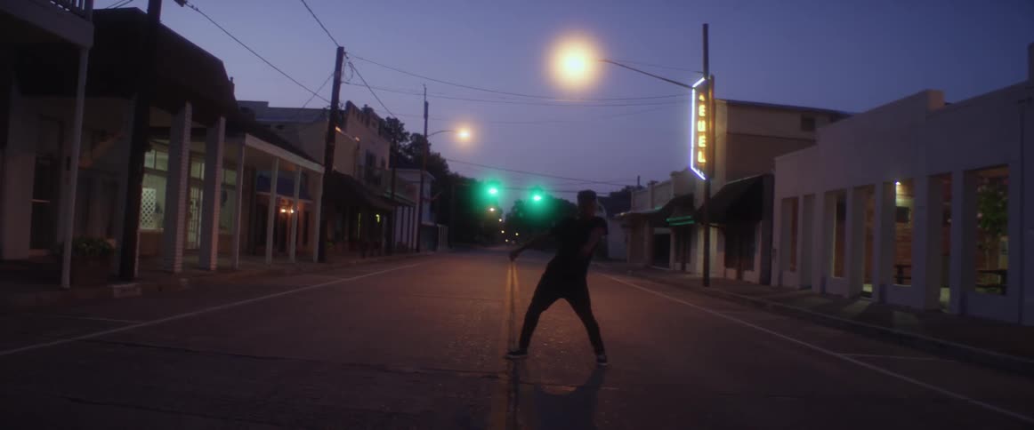 A person is dancing on an empty street at night