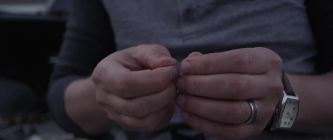 A man ties a lure to a piece of string
