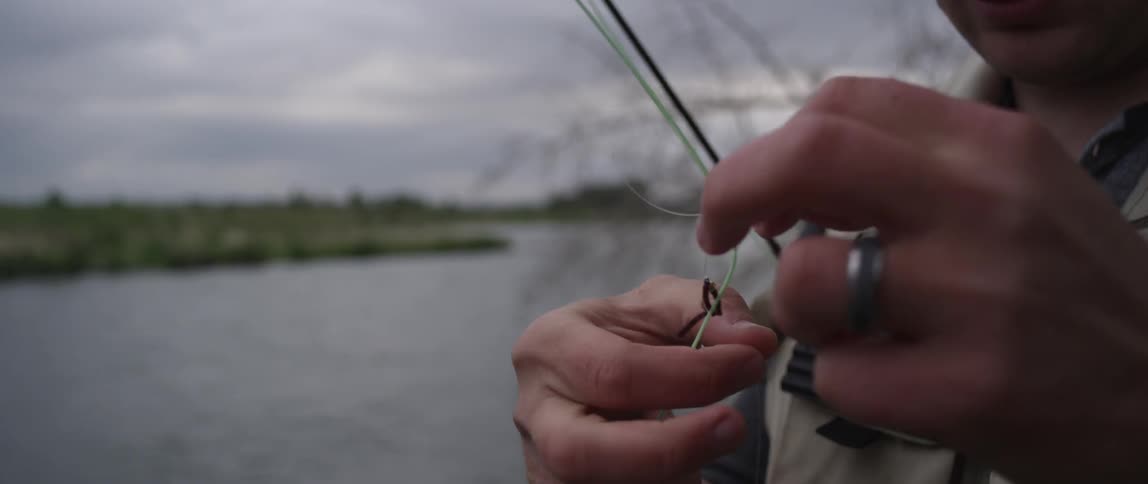 Man tying fishing hook to fishing line