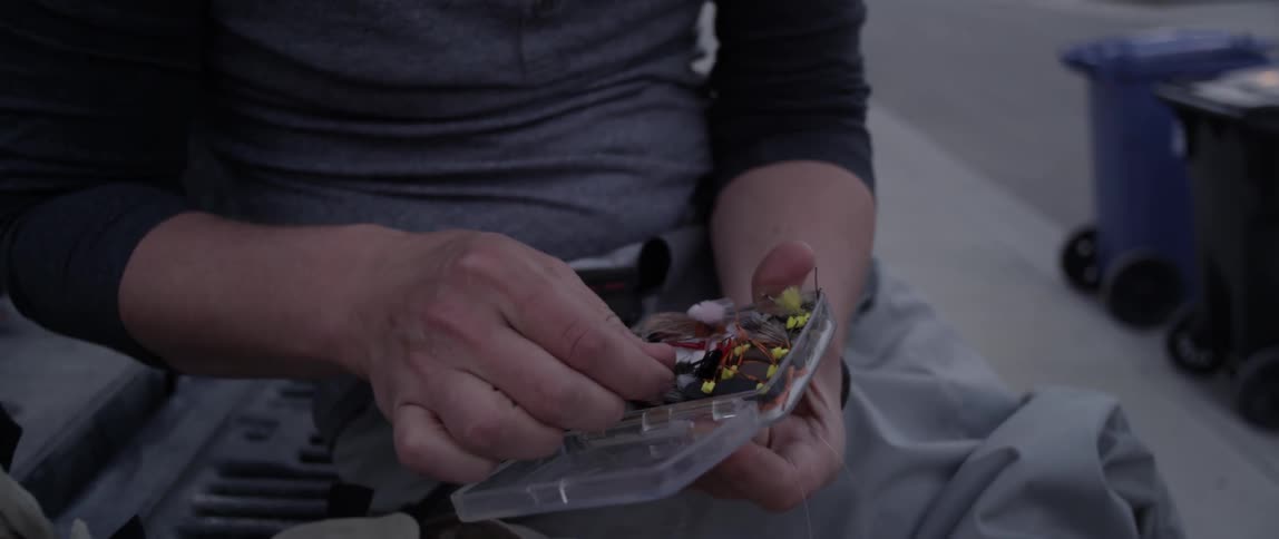 A man looks through a box of fishing baits