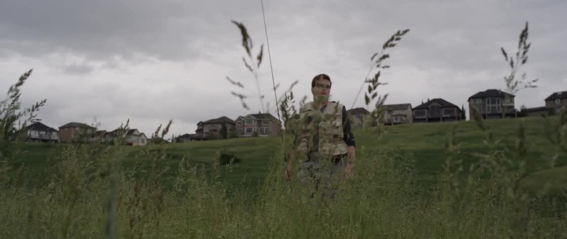A man is walking through grass on a cloudy day