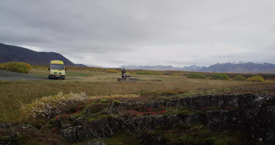 A van is parked on a field as a person stands nearby