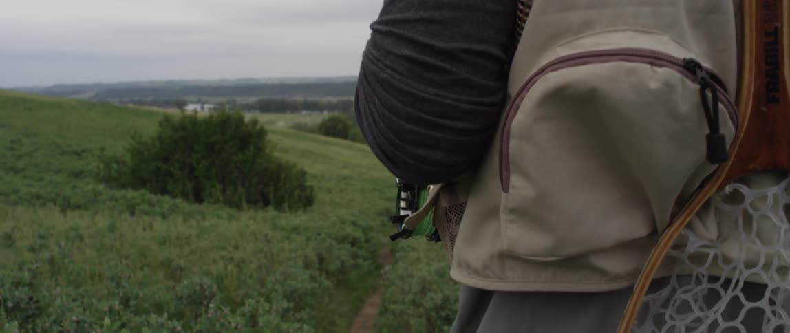 A man hikes down a grassy hill