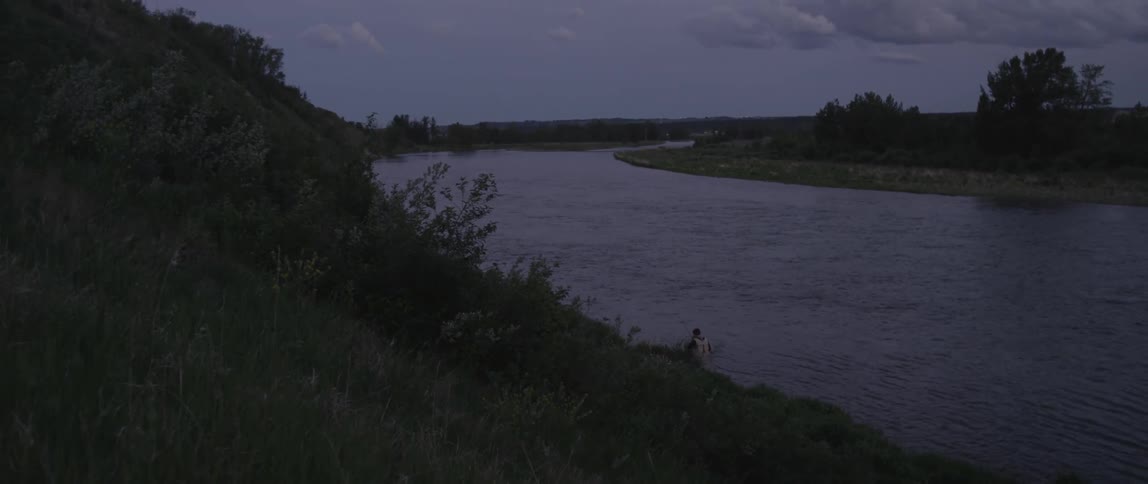 A man is hiking along a riverbed below