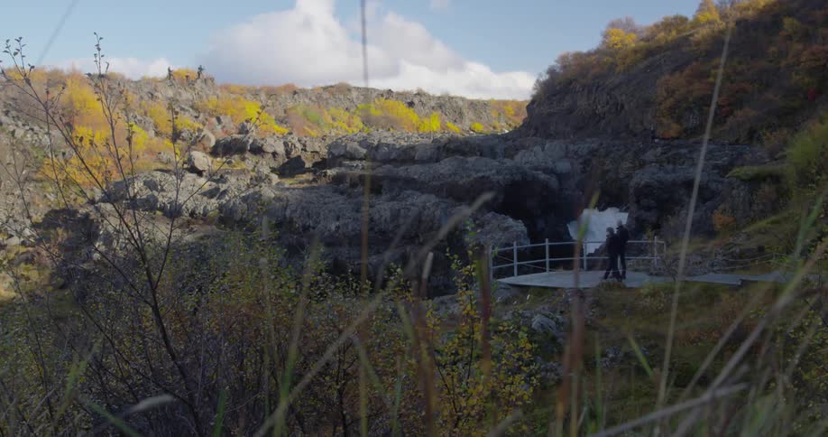 A person is hiking to a railing near a waterfall