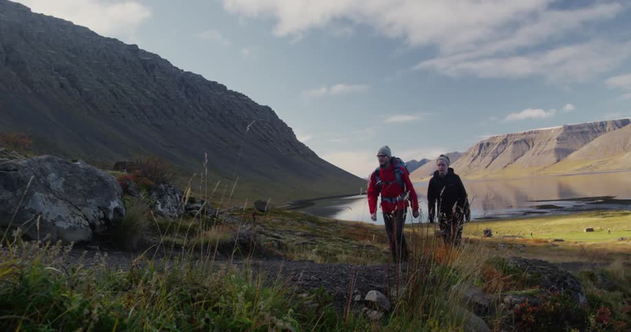 People are hiking away from a lake near a mountain range