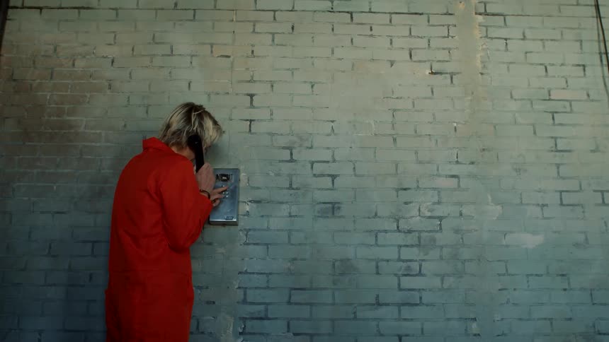 A man in jail is using a telephone to talk to someone