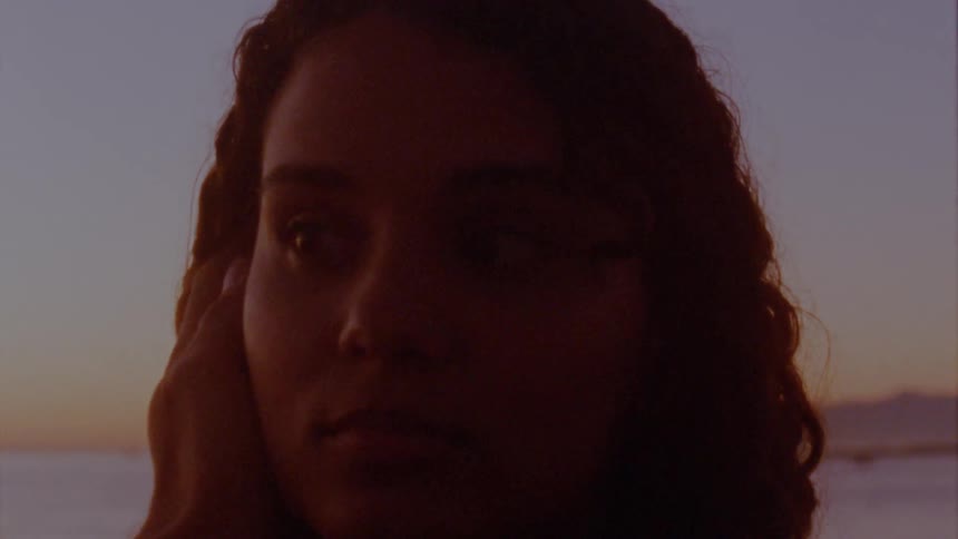 A mans hand reaches out and caresses a womans cheek and hair