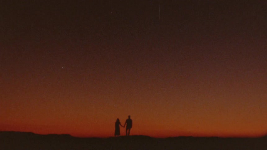 Two people holding hands at sunset