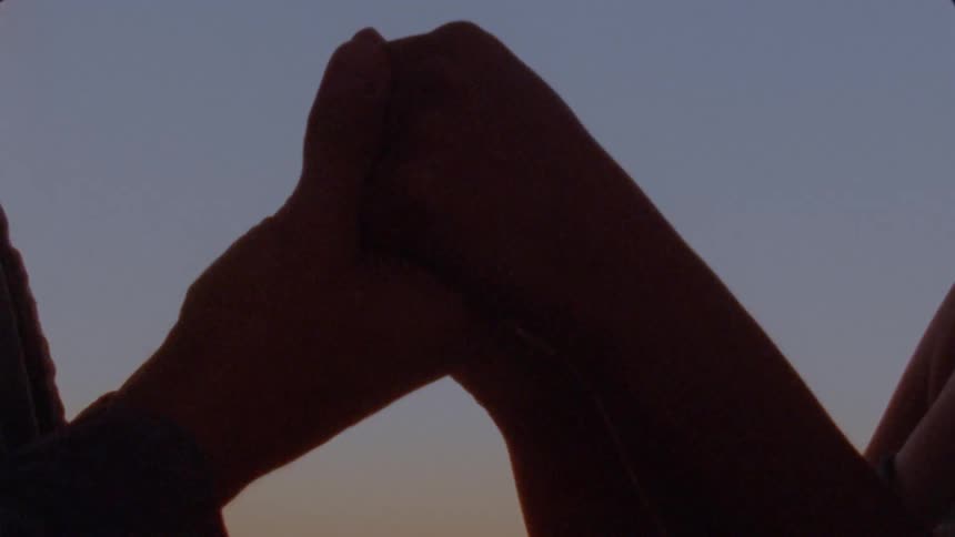 A view of two people holding hands outdoors