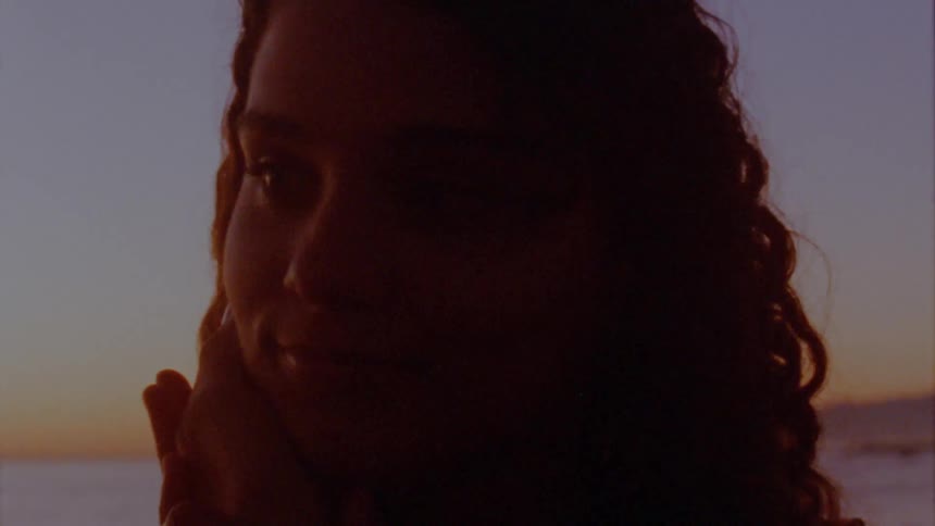 Woman touches womans cheek on the beach at sunset