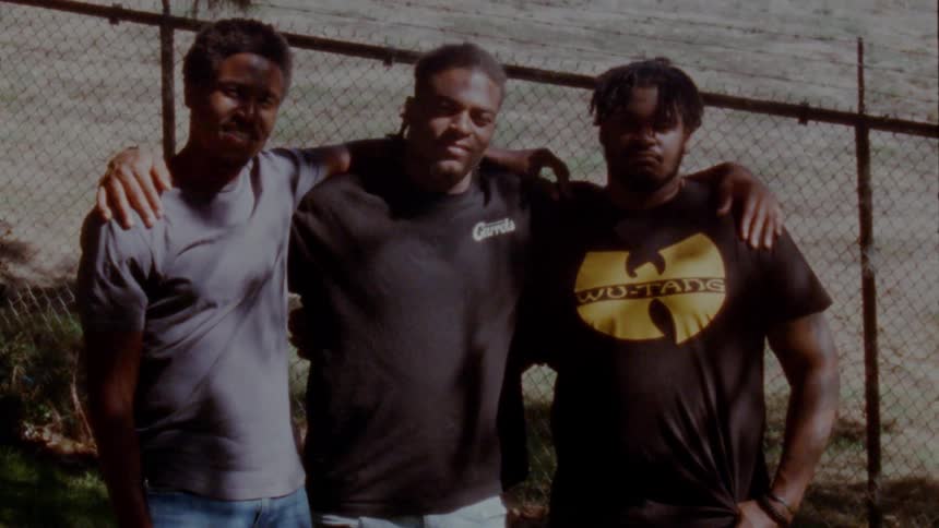 Three friends with arms around each other standing on the backyard looking at the camera