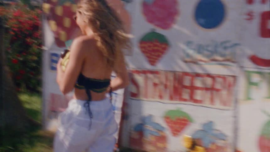 Two teenage girls carrying fruit are running from a farm market to a van