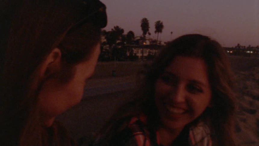 Two young women smiling and laughing outside at dusk